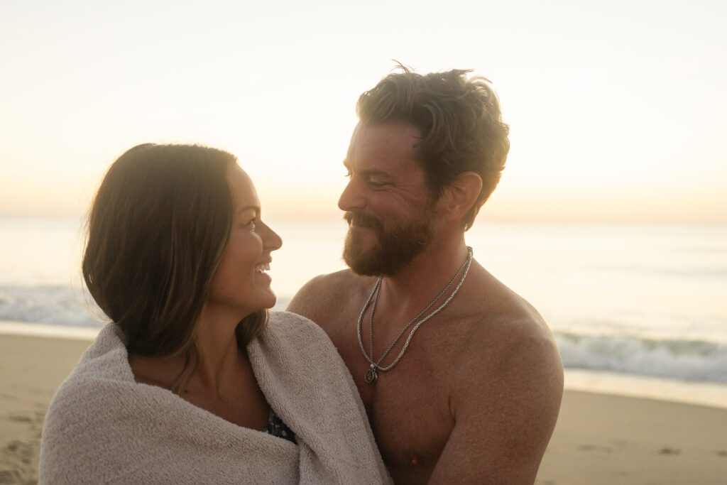 a man and a woman wrapped in a towel on the beach