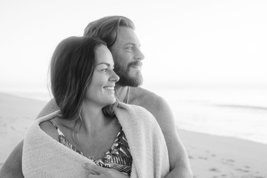 a man and woman wrapped in a blanket on the beach