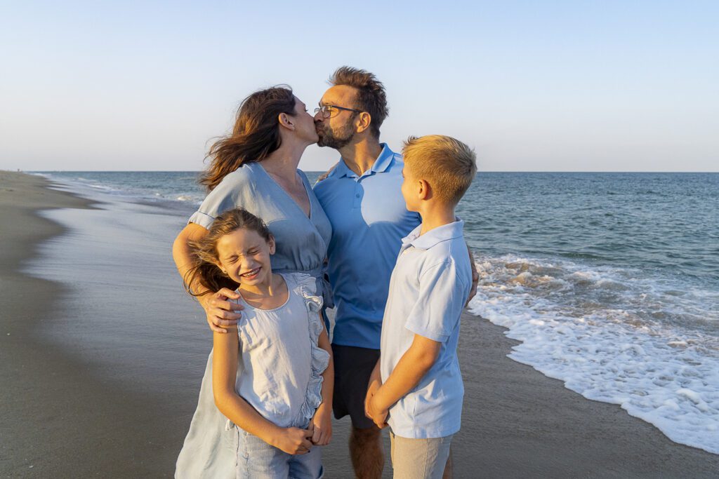 a family of four standing on a beach next to the ocean