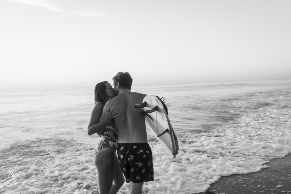 a man and a woman standing on a beach next to the ocean