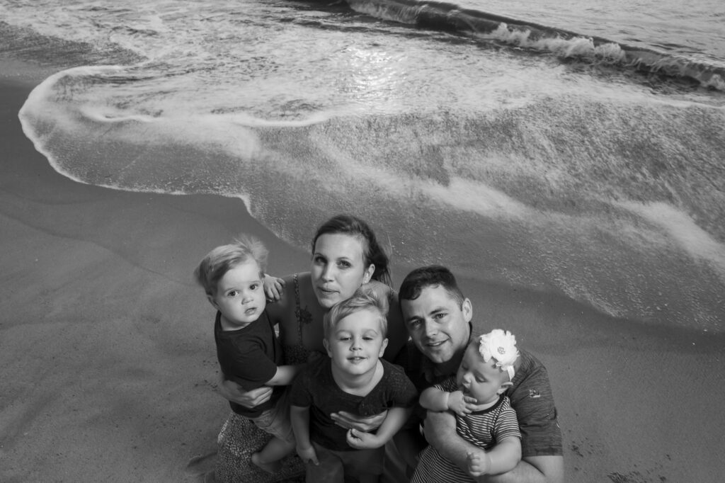 a black and white photo of a family on the beach