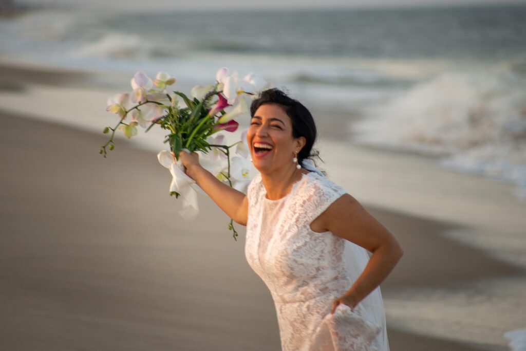 a woman holding a bouquet of flowers on a beach