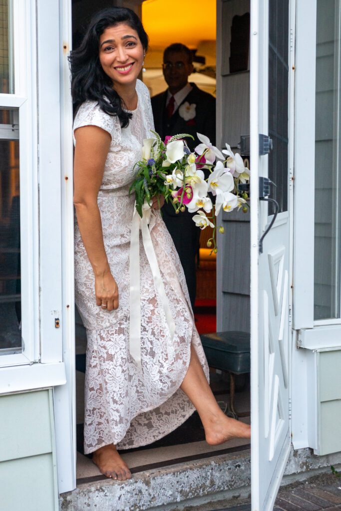 a woman in a white dress exiting a house