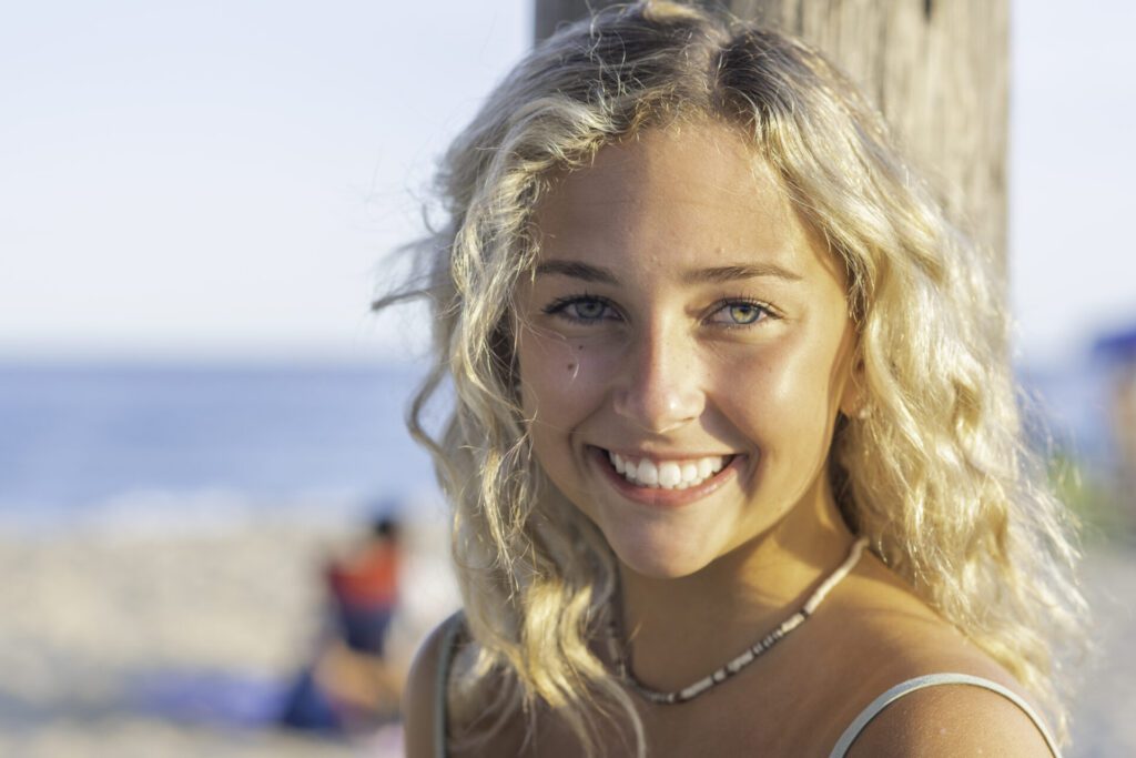 a beautiful blonde woman standing next to a wooden pole